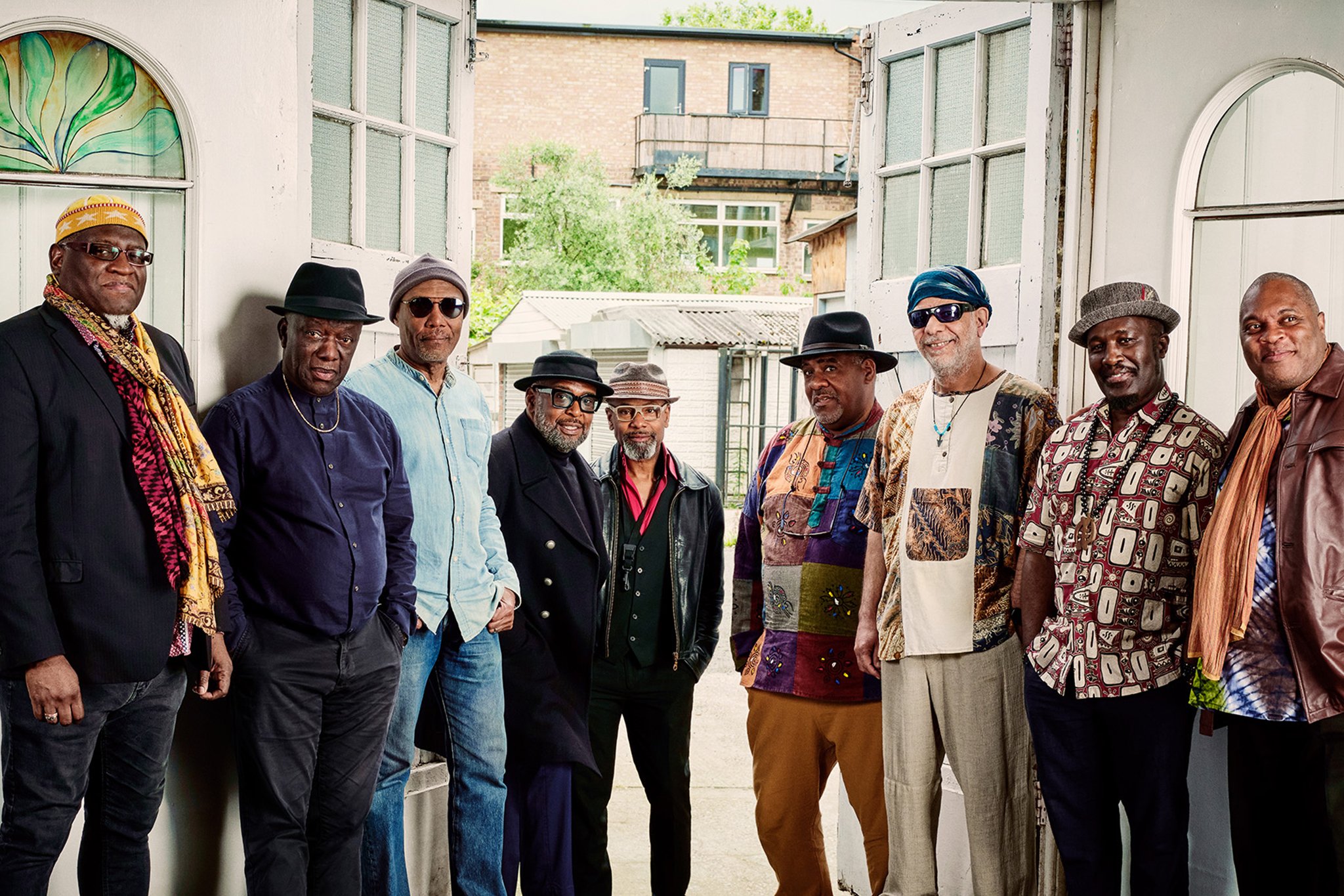 Nine members of the band Cymande pose for a promotional photo.
